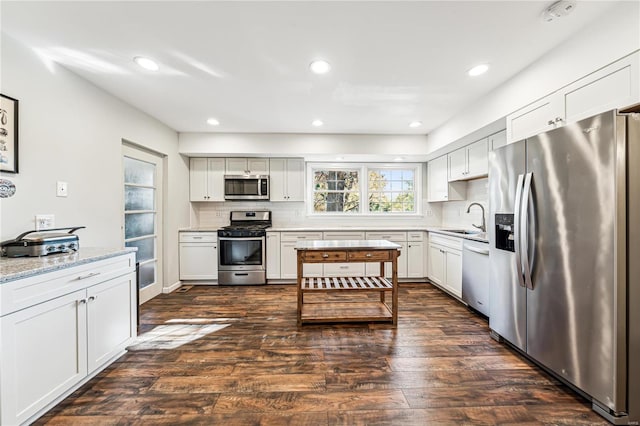 kitchen featuring light stone countertops, appliances with stainless steel finishes, dark hardwood / wood-style floors, and sink