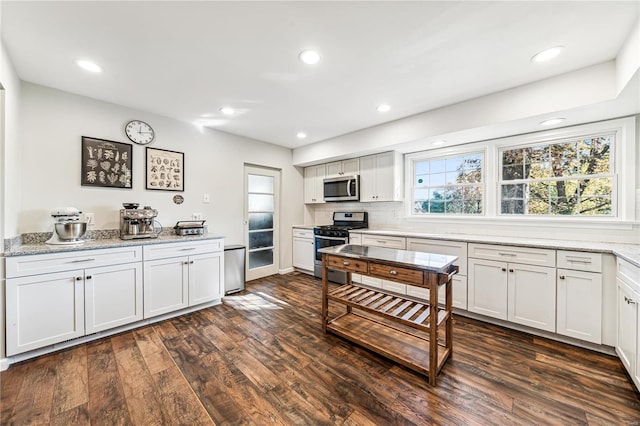 kitchen featuring light stone countertops, white cabinets, dark hardwood / wood-style floors, and appliances with stainless steel finishes