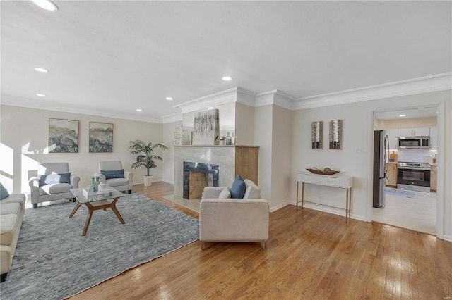 living room featuring light wood-style flooring, baseboards, crown molding, and a high end fireplace