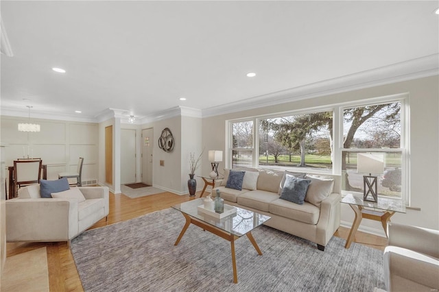 living room with a chandelier, ornamental molding, light wood finished floors, and recessed lighting