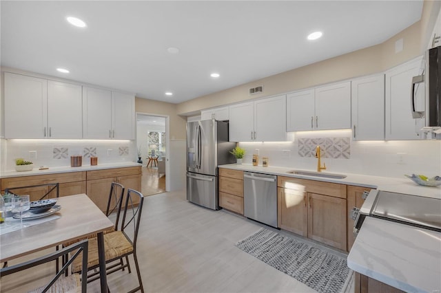 kitchen with appliances with stainless steel finishes, a sink, and white cabinetry