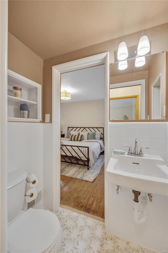 bathroom featuring backsplash, toilet, a sink, connected bathroom, and tile patterned floors