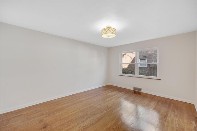 spare room featuring visible vents, light wood-style flooring, and baseboards