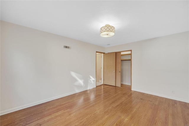 unfurnished room with wood finished floors, visible vents, and baseboards