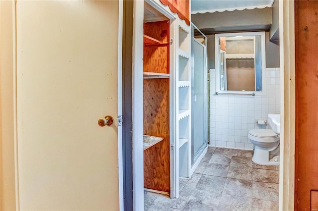 bathroom with toilet and tile walls