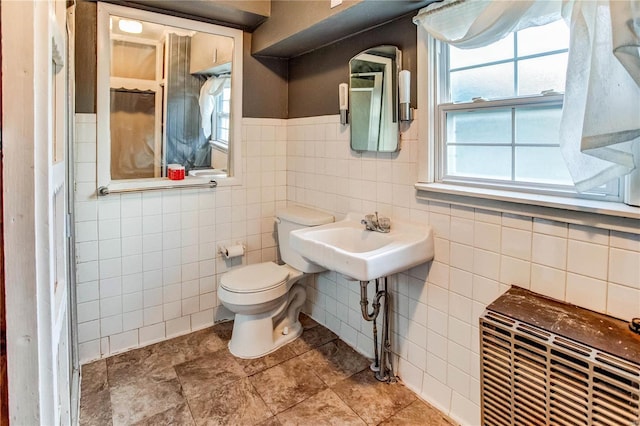 bathroom featuring toilet, tile walls, and sink