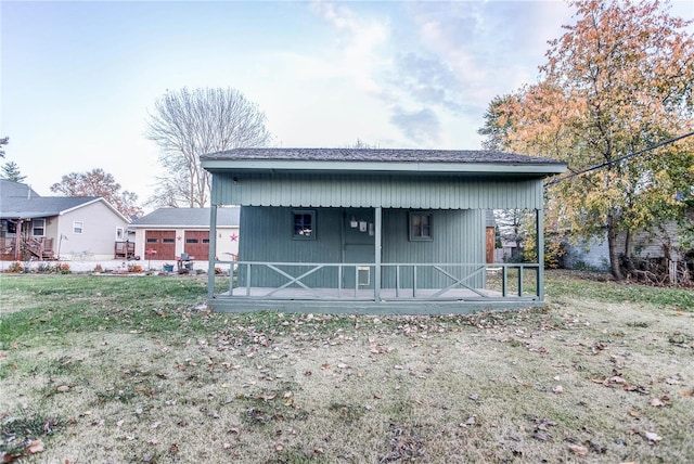 back of house featuring covered porch and a lawn