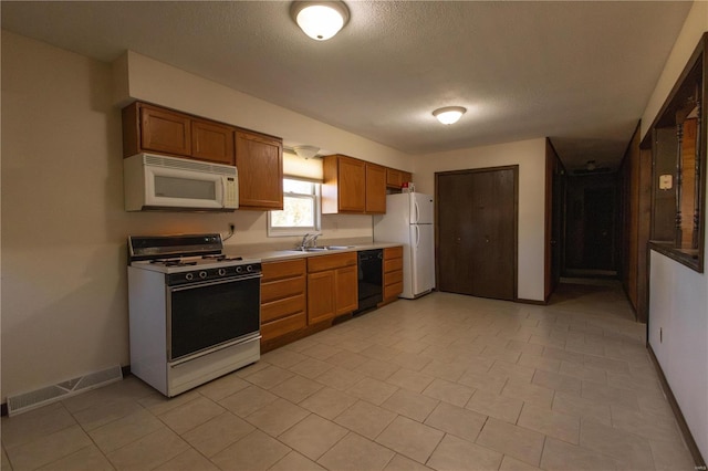 kitchen with a textured ceiling, sink, white appliances, and light tile patterned flooring