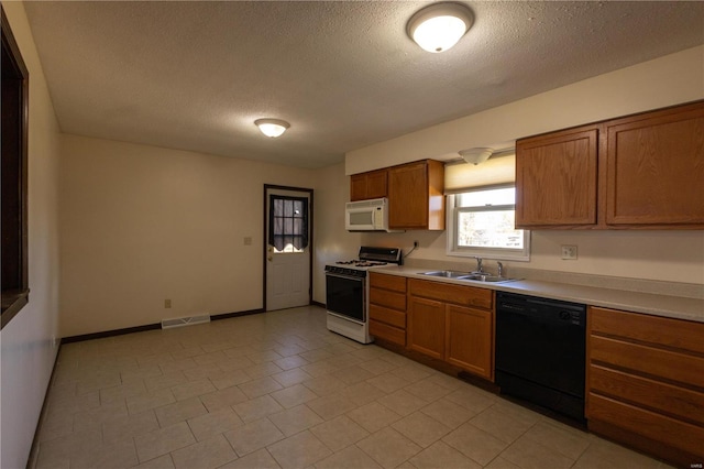 kitchen featuring white appliances, sink, light tile patterned floors, and a textured ceiling