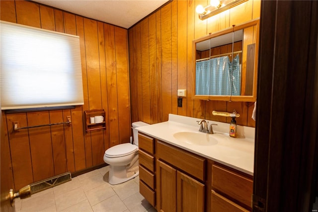 bathroom with toilet, tile patterned flooring, wood walls, a textured ceiling, and vanity