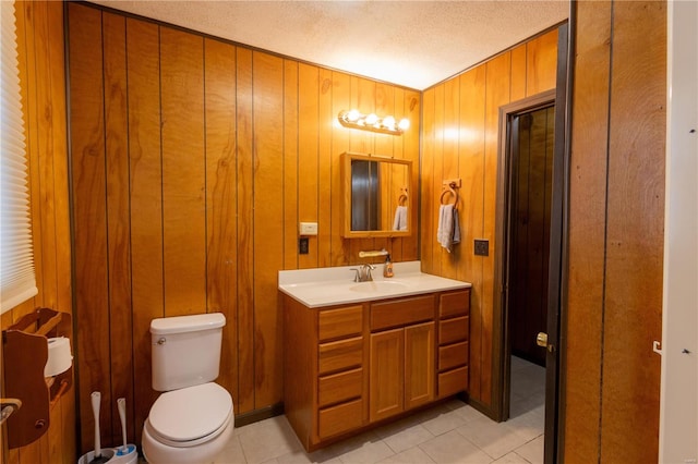 bathroom featuring vanity, wooden walls, a textured ceiling, and toilet