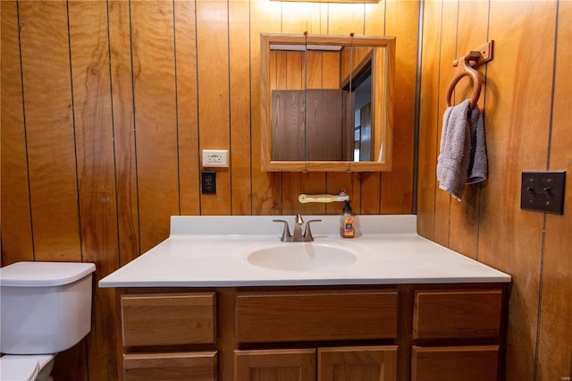 bathroom with wood walls, vanity, and toilet