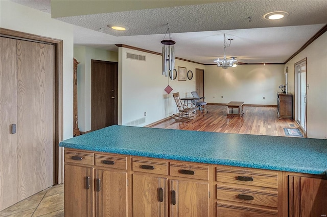 kitchen featuring light hardwood / wood-style floors, a textured ceiling, and ornamental molding