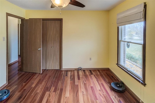 unfurnished bedroom featuring dark hardwood / wood-style flooring, ceiling fan, and a closet