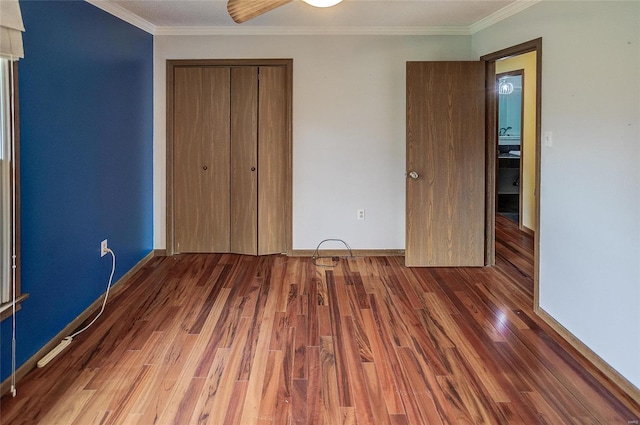 unfurnished bedroom with dark hardwood / wood-style flooring, ceiling fan, crown molding, and a closet