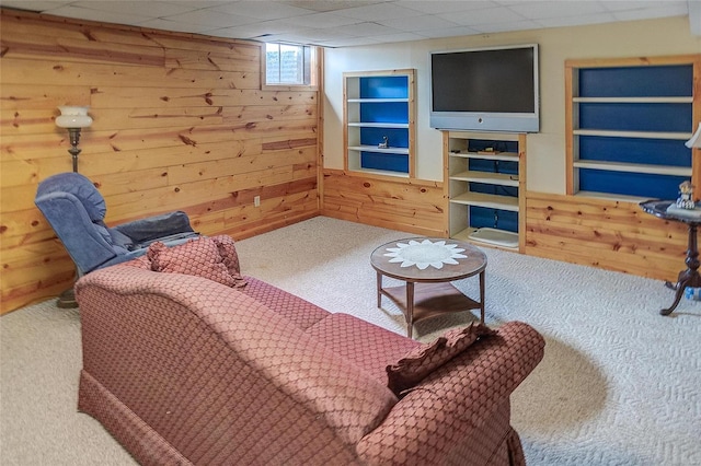 carpeted living room with wooden walls and a paneled ceiling