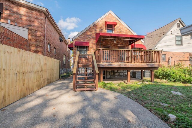 rear view of house featuring a lawn and a deck