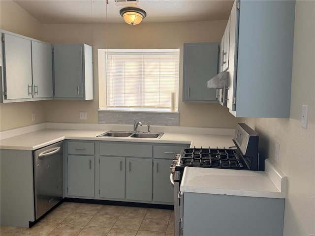 kitchen with sink, gray cabinetry, stainless steel range with gas stovetop, extractor fan, and light tile patterned flooring