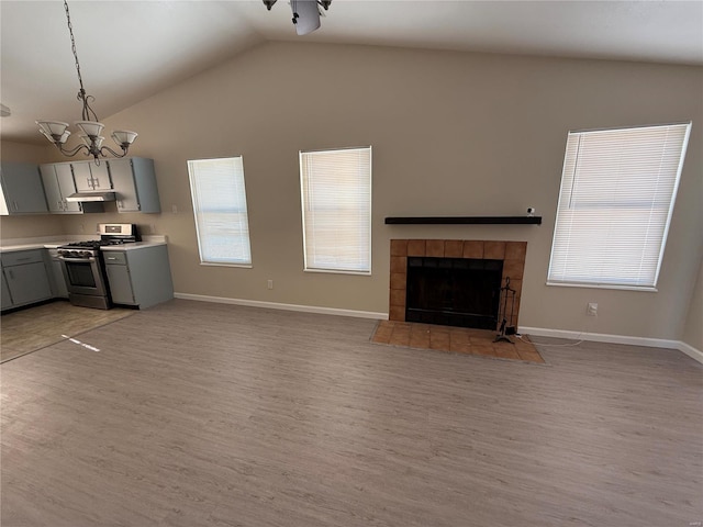 unfurnished living room with a fireplace, light hardwood / wood-style floors, a chandelier, and vaulted ceiling