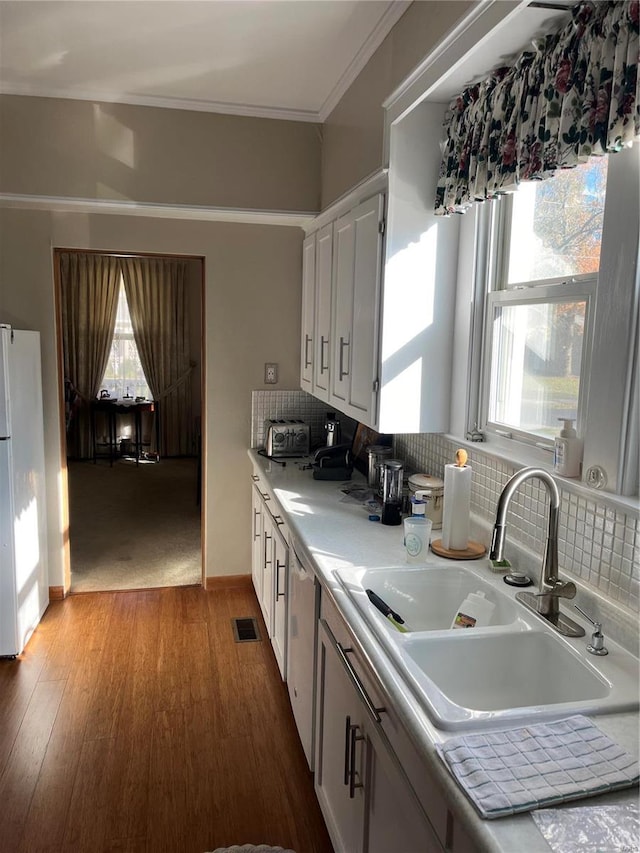 kitchen with white cabinets, sink, hardwood / wood-style floors, and white appliances