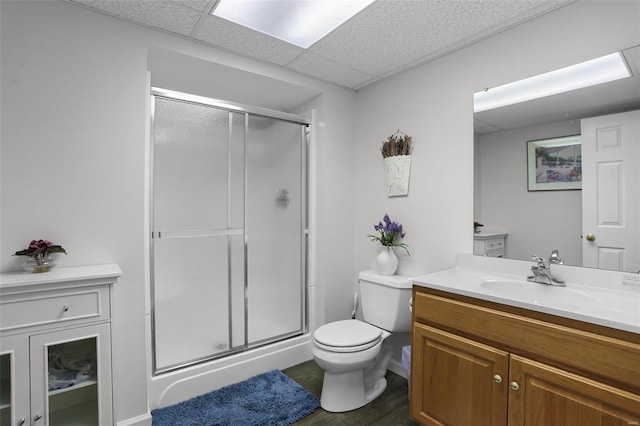 bathroom featuring a paneled ceiling, hardwood / wood-style floors, vanity, a shower with shower door, and toilet