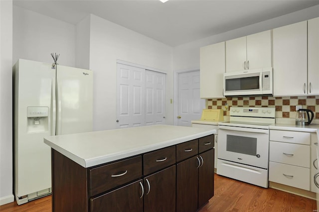 kitchen with hardwood / wood-style flooring, backsplash, white appliances, and dark brown cabinets