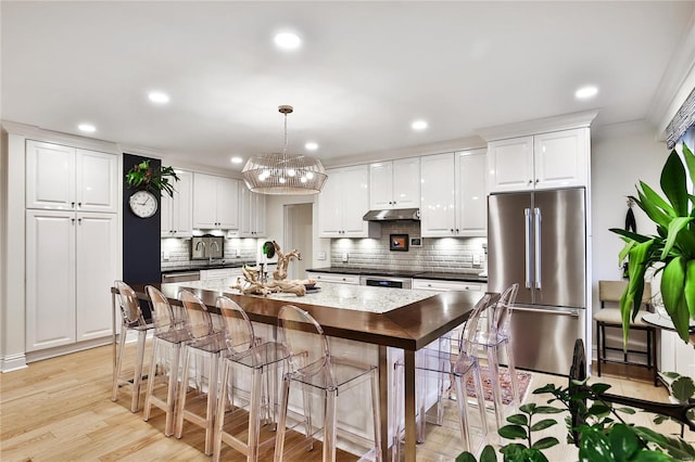 kitchen featuring white cabinets, stainless steel appliances, pendant lighting, and light hardwood / wood-style flooring