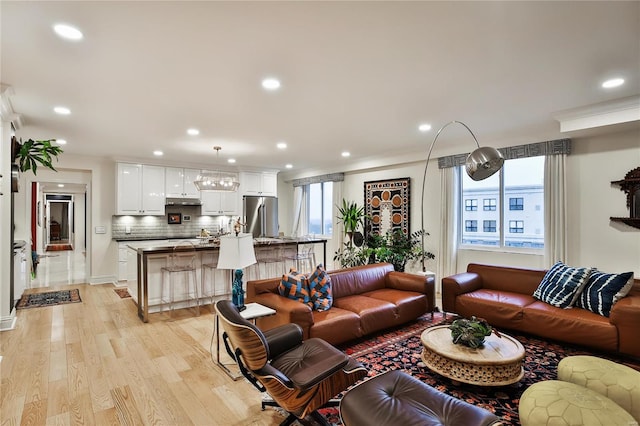 living room with light wood-type flooring and ornamental molding