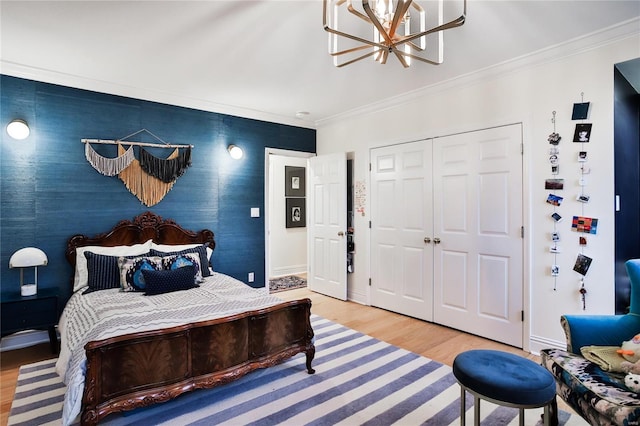 bedroom with a closet, a chandelier, hardwood / wood-style flooring, and crown molding