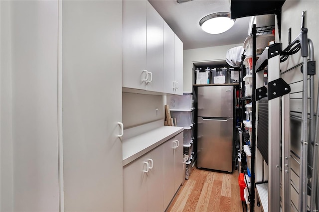 kitchen featuring white cabinets, light hardwood / wood-style floors, and stainless steel refrigerator