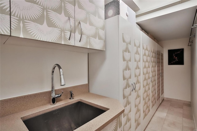 kitchen with light tile patterned floors, white cabinetry, and sink