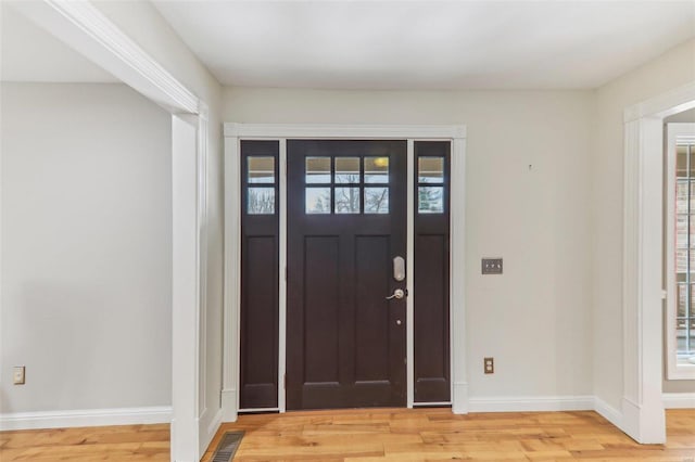 foyer entrance with a healthy amount of sunlight, light wood-style flooring, visible vents, and baseboards