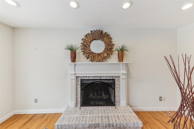 unfurnished living room featuring baseboards, a brick fireplace, wood finished floors, and recessed lighting