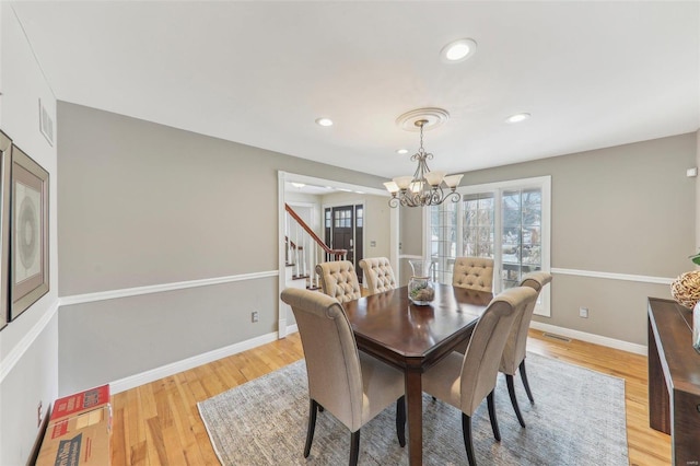 dining room with light wood-style floors, a chandelier, visible vents, and baseboards