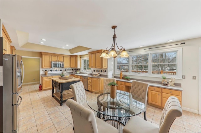 kitchen featuring stainless steel appliances, pendant lighting, light countertops, and a chandelier