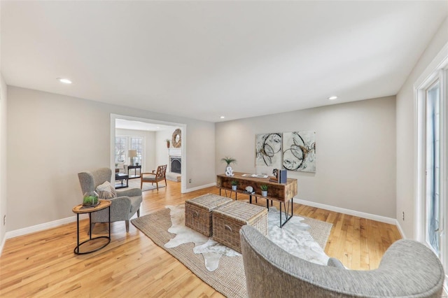 living room with baseboards, a fireplace with raised hearth, wood finished floors, and recessed lighting