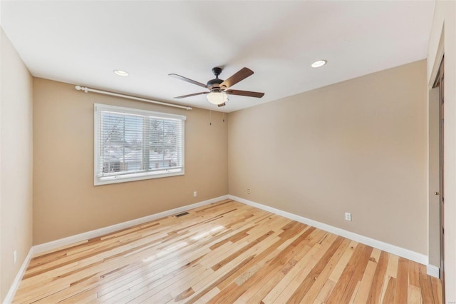 empty room featuring baseboards, ceiling fan, visible vents, and light wood-style floors