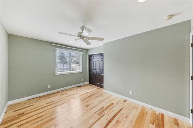 unfurnished bedroom featuring ceiling fan, a closet, light wood-style flooring, and baseboards