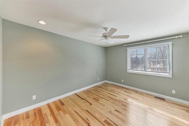 empty room with light wood-style flooring, visible vents, baseboards, and ceiling fan