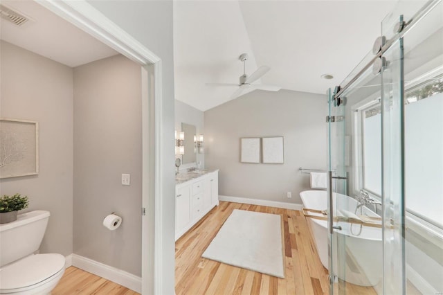 bathroom featuring visible vents, toilet, lofted ceiling, vanity, and a freestanding tub