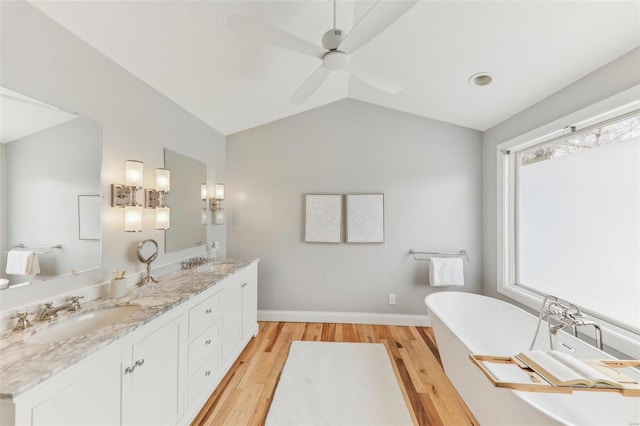 full bathroom with wood finished floors, vaulted ceiling, a sink, and double vanity