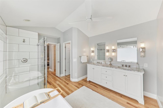 full bath featuring double vanity, lofted ceiling, a sink, a shower stall, and wood finished floors