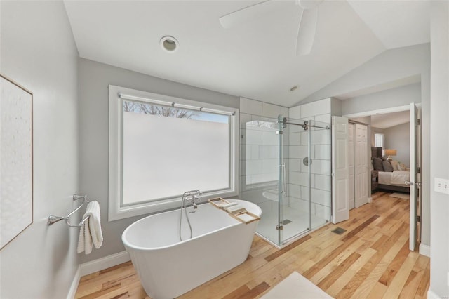 full bath featuring lofted ceiling, wood finished floors, a freestanding bath, a stall shower, and ensuite bath