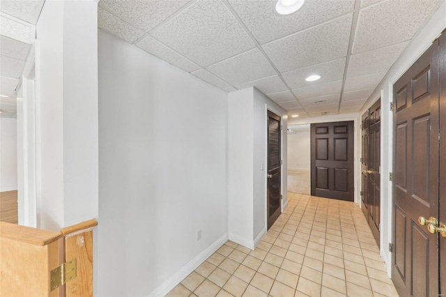 corridor featuring recessed lighting, a drop ceiling, baseboards, and light tile patterned floors