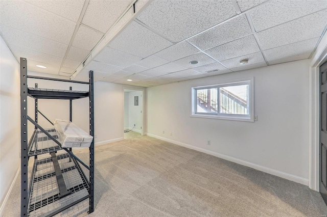 below grade area featuring visible vents, baseboards, a drop ceiling, and carpet flooring