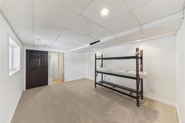 basement with a drop ceiling, carpet, and baseboards