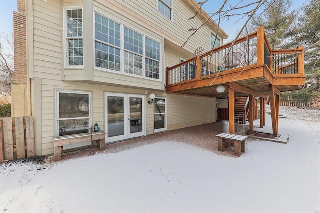 snow covered property featuring stairs, french doors, and a deck