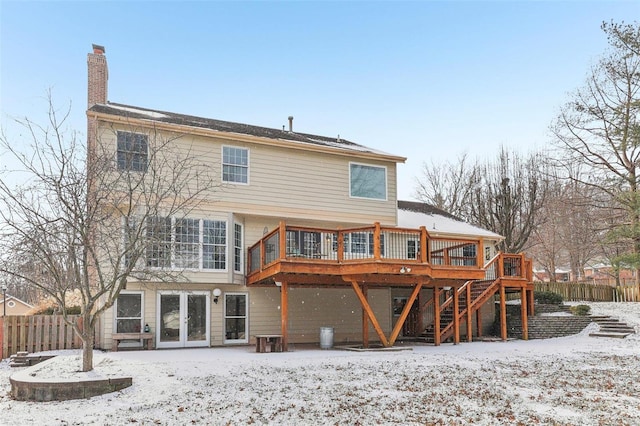 snow covered back of property featuring stairway, a chimney, fence, and a deck