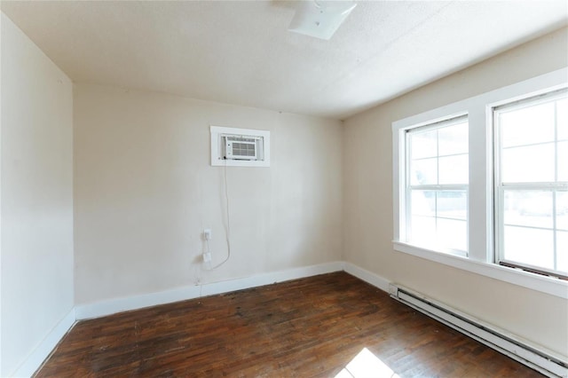 unfurnished room with a skylight, dark hardwood / wood-style floors, an AC wall unit, and a baseboard radiator