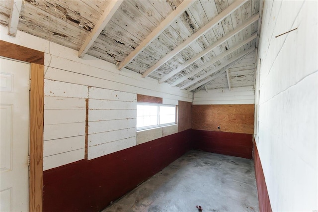 interior space with lofted ceiling, wood walls, and concrete floors